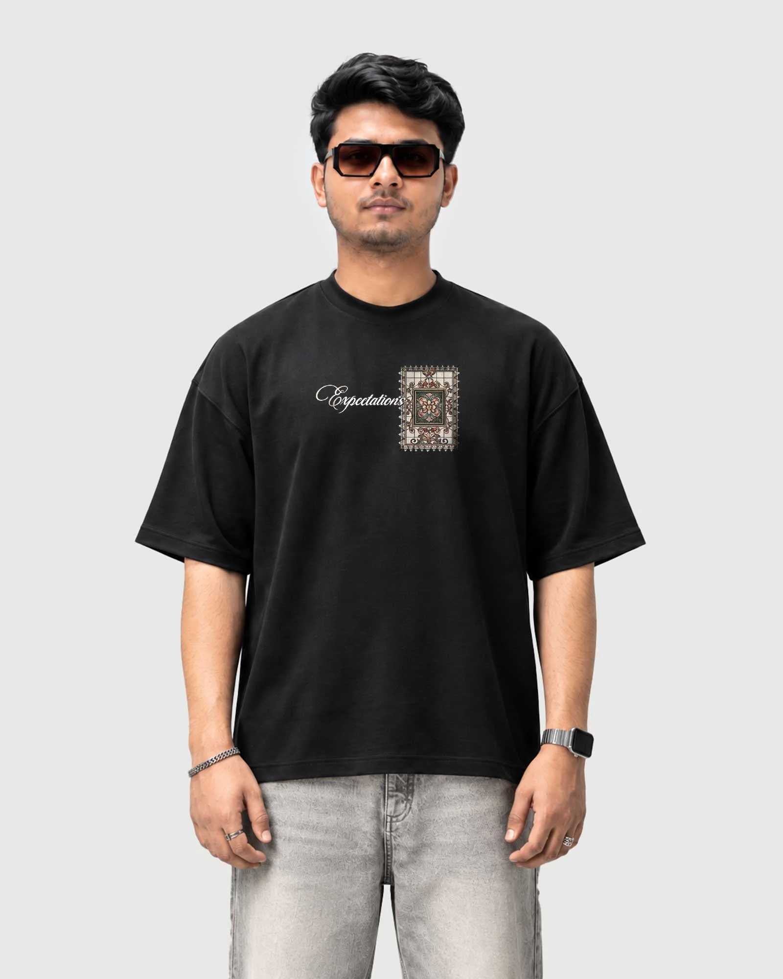 Model wearing the black Outflee Framed Expectations drop shoulder T-shirt, front view showing the Expectations script and ornate frame chest artwork.