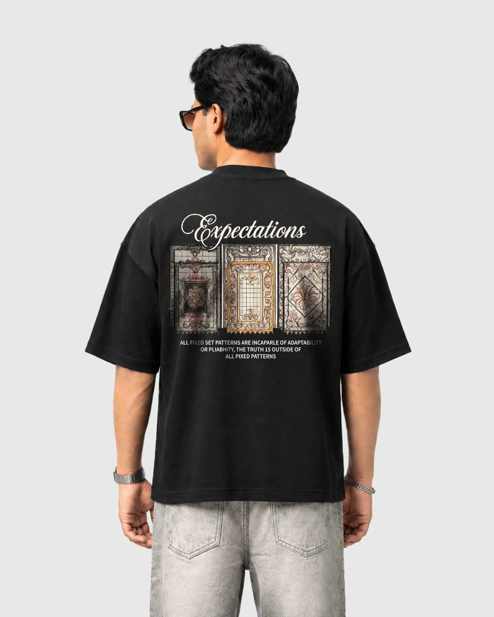 Model wearing the black Outflee Framed Expectations drop shoulder T-shirt, back view showing large Expectations lettering and three detailed vintage frame artworks.