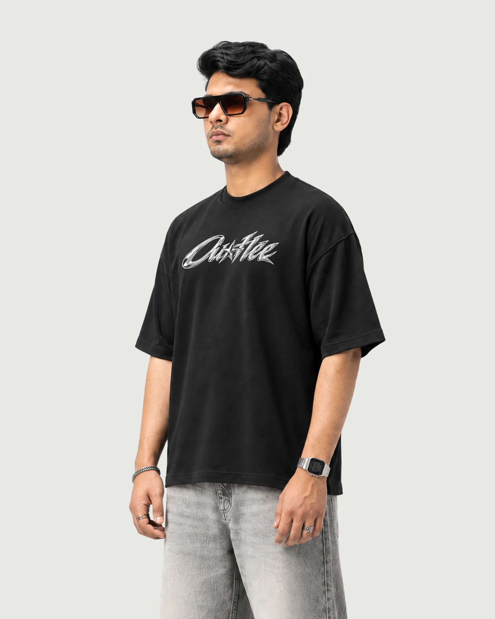Three-quarter view of a model wearing the black Outflee Five Star Escape drop shoulder T-shirt, showing the relaxed fit and chrome chest print.