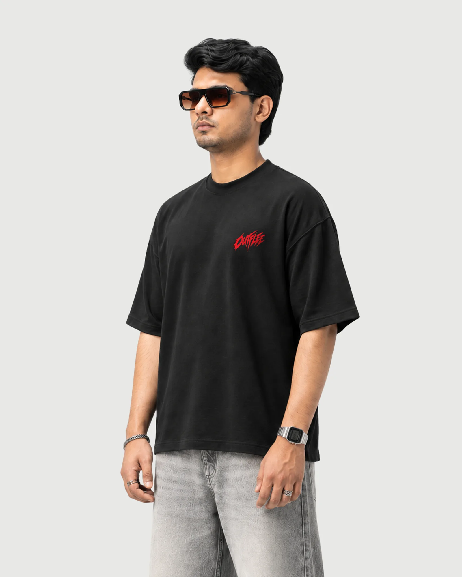 Three-quarter view of a model wearing the black Outflee Street Reign drop shoulder T-shirt, showing the relaxed drop shoulder fit and red chest print.