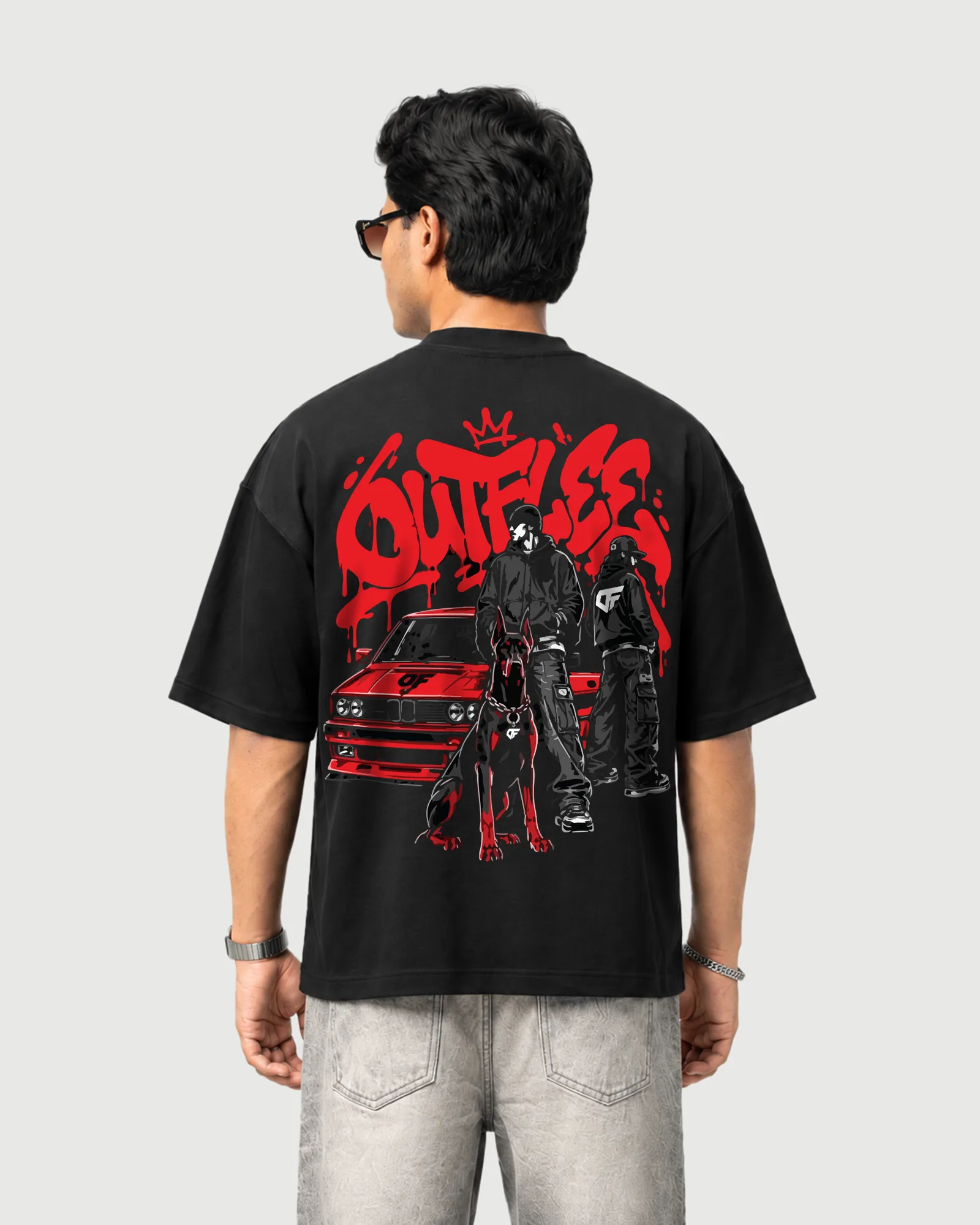 Model wearing the black Outflee Street Reign drop shoulder T-shirt, back view showing the red graffiti artwork, car, two figures and Doberman graphic.