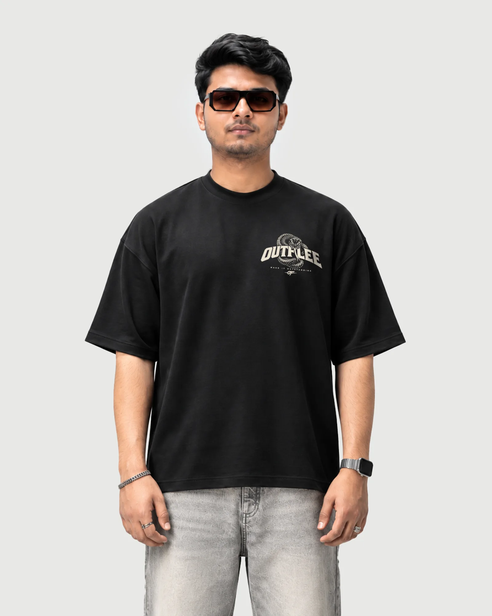 Model wearing the black Outflee Serpent Reign drop shoulder T-shirt, front view showing the cream Outflee logo and snake chest graphic.