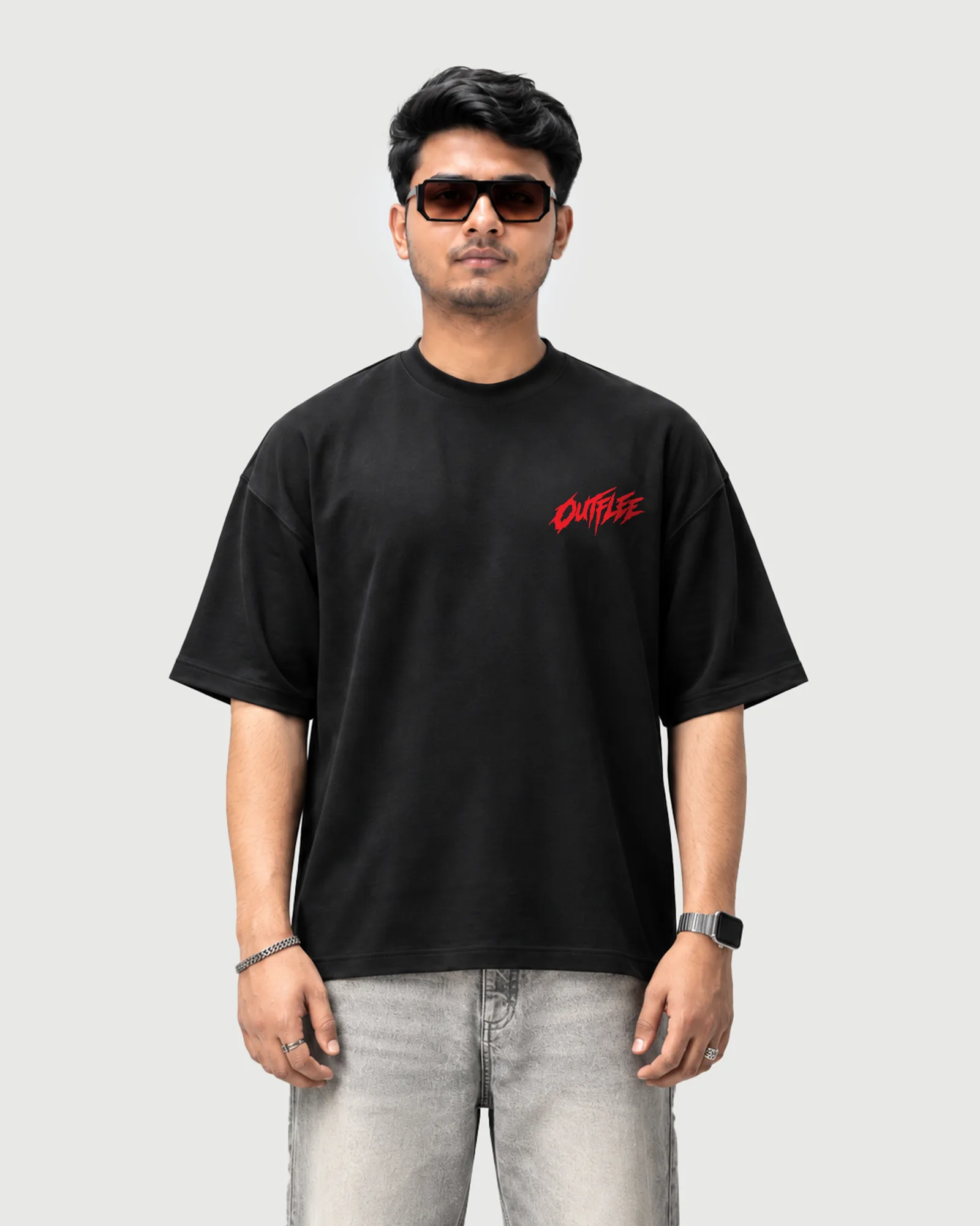 Model wearing the black Outflee Street Reign drop shoulder T-shirt, front view showing the small red Outflee chest logo.