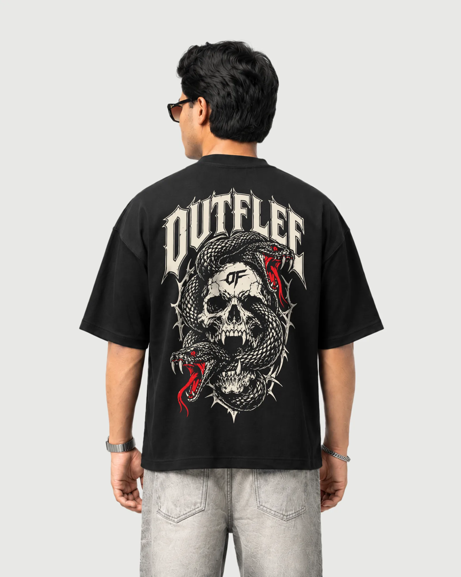 Model wearing the black Outflee Serpent Reign drop shoulder T-shirt, back view showing the large skull and intertwined snake artwork with red accents.