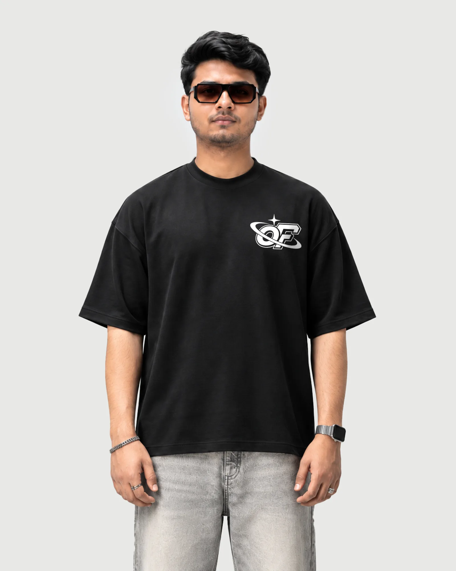 Model wearing the black Outflee Infinite Orbit drop shoulder T-shirt, front view showing the white OF planet-ring chest logo.