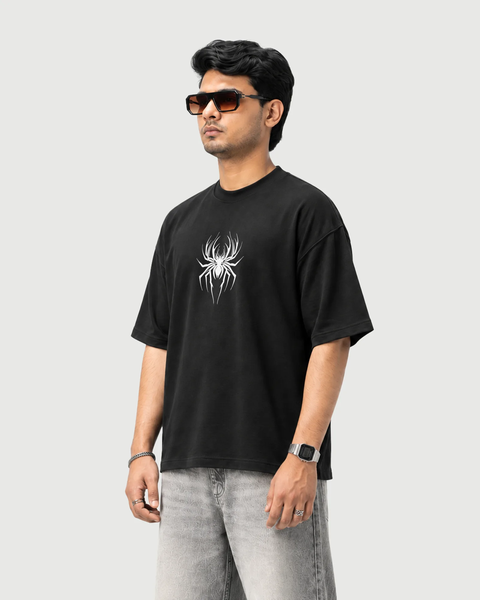 Three-quarter view of a model wearing the black Outflee Enter the Hollow drop shoulder T-shirt, showing the relaxed drop shoulder fit and white spider front graphic.