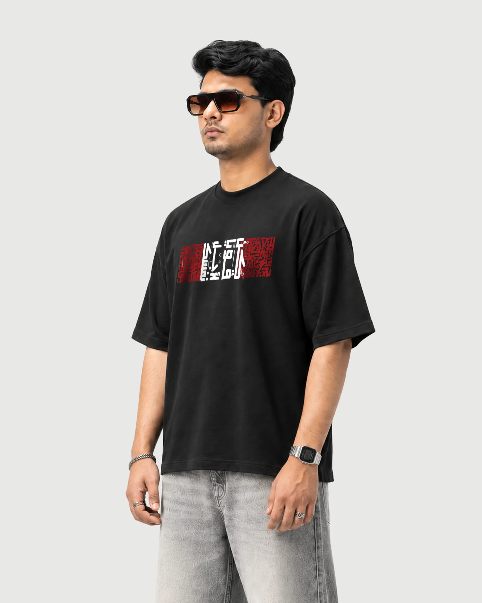 Three-quarter view of a model wearing the black Outflee Arabic Calligraphy drop shoulder T-shirt, showing the relaxed fit and calligraphic front artwork.