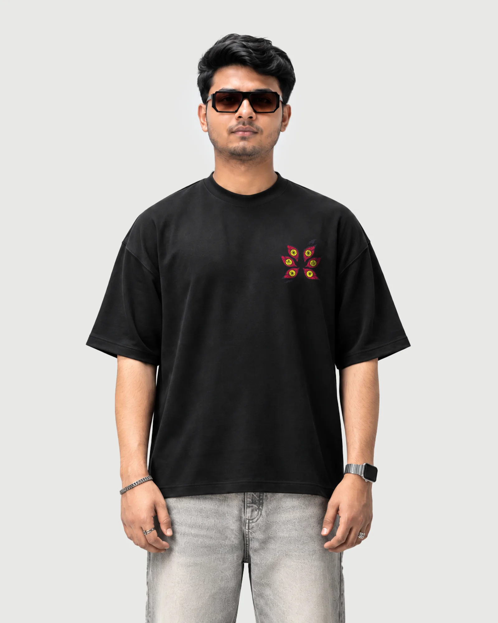 Model wearing the black Outflee Sixfold Gaze drop shoulder T-shirt, front view showing the small six-eye chest graphic.