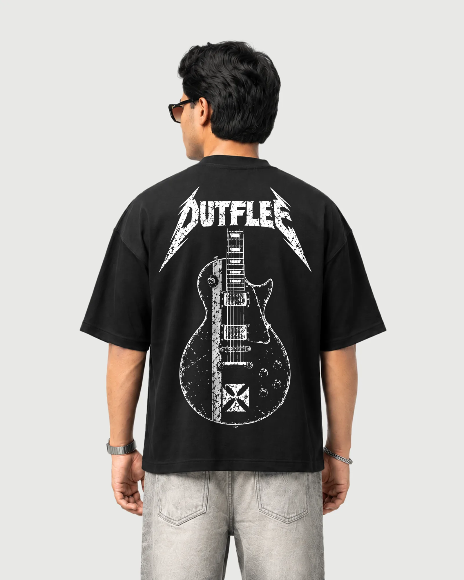 Model wearing the black Outflee Distorted Riff drop shoulder T-shirt, back view showing the large distressed electric guitar artwork and Outflee lettering.