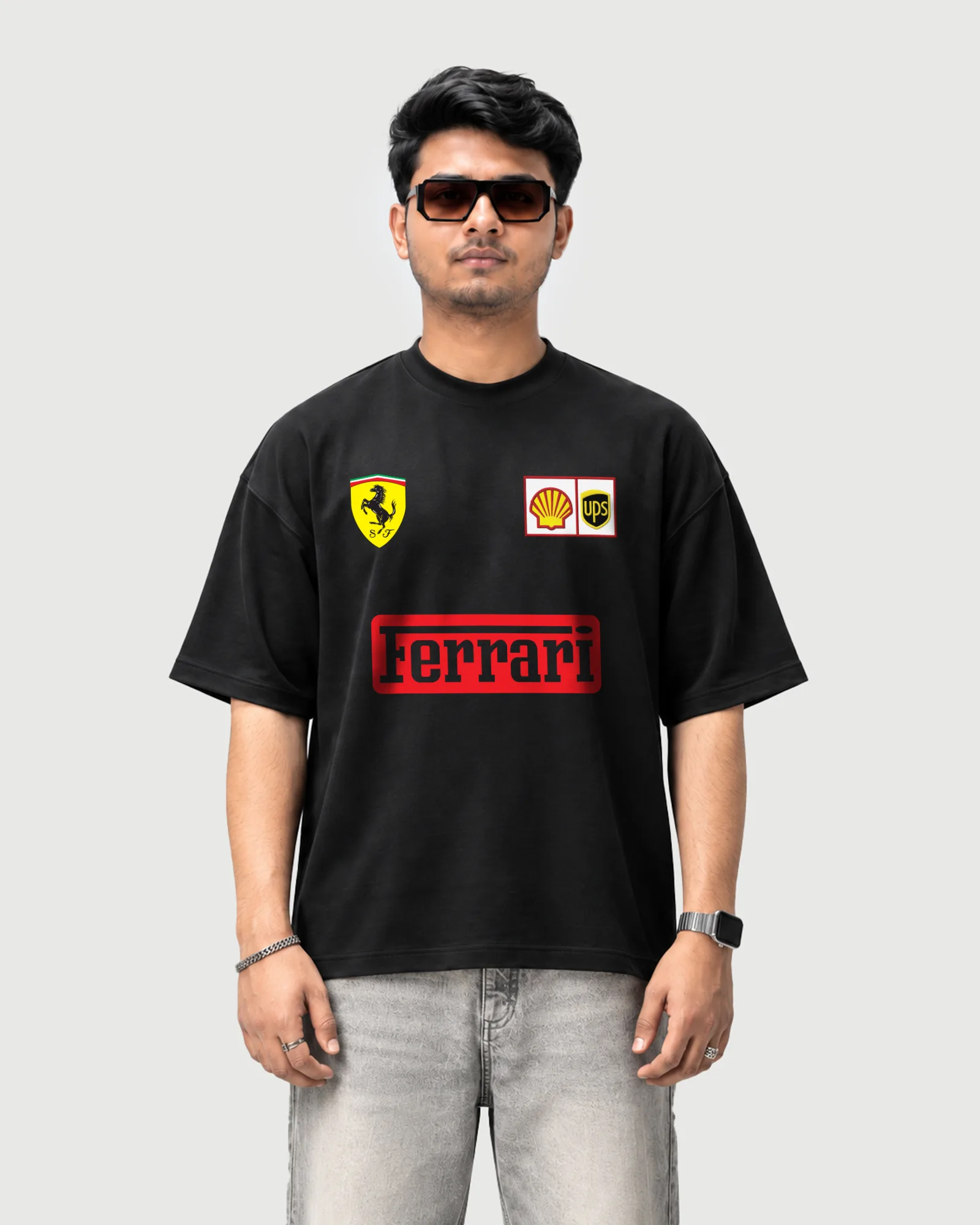 Model wearing the black Outflee Ferrari Formula 1 graphic drop shoulder T-shirt, front view showing the Ferrari shield, sponsor logos and red Ferrari wordmark.