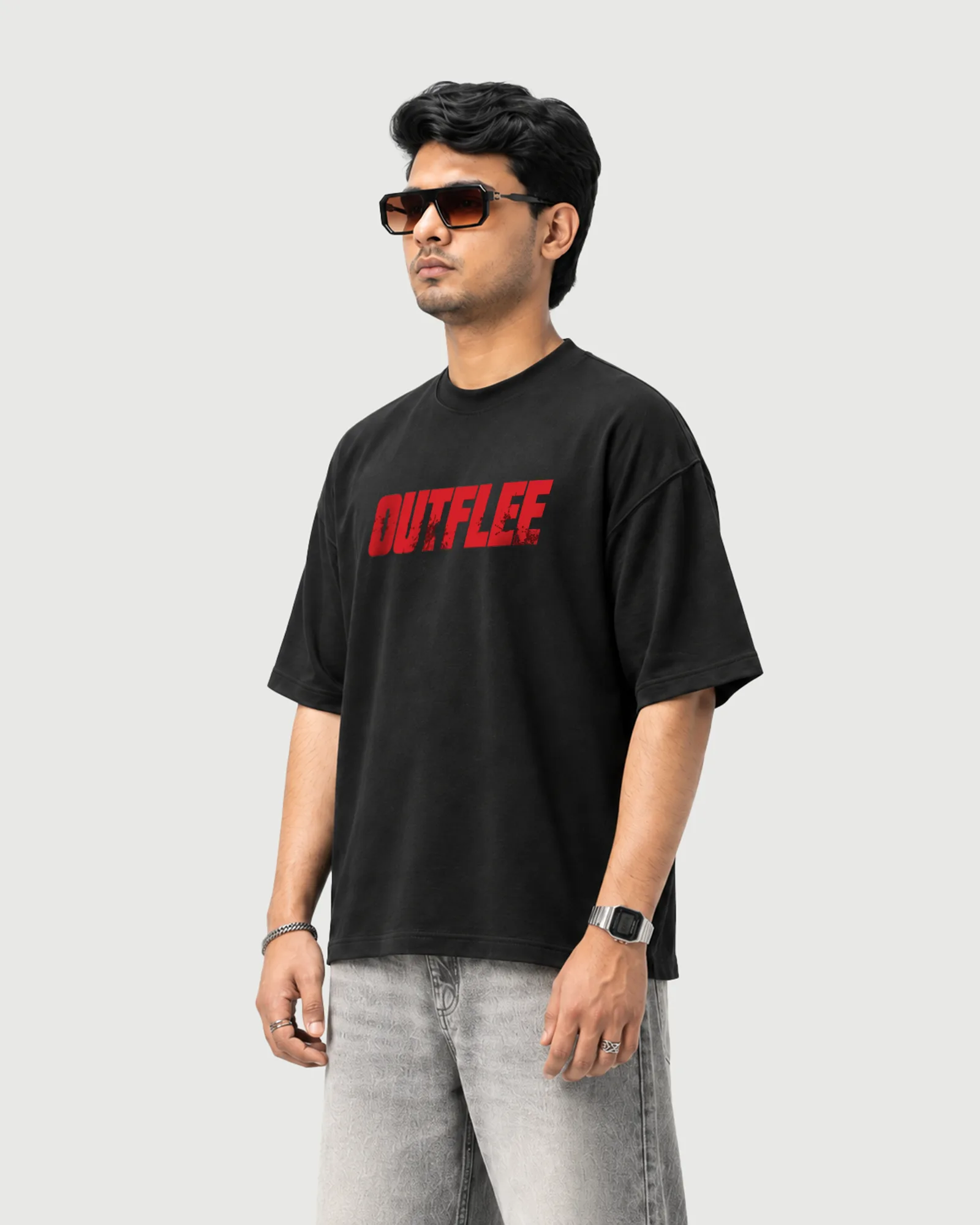 Three-quarter view of a model wearing the black Outflee Same Streets Different Minds drop shoulder T-shirt, showing the relaxed fit and bold red front typography.