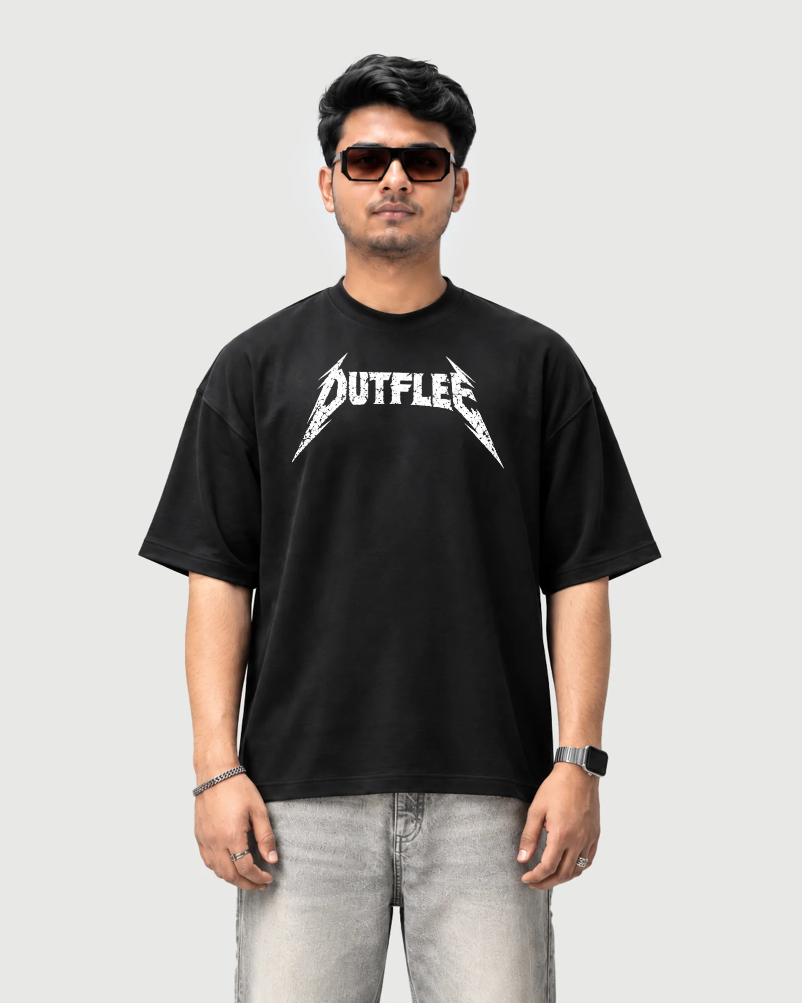 Model wearing the black Outflee Distorted Riff drop shoulder T-shirt, front view showing the distressed white Outflee chest graphic.